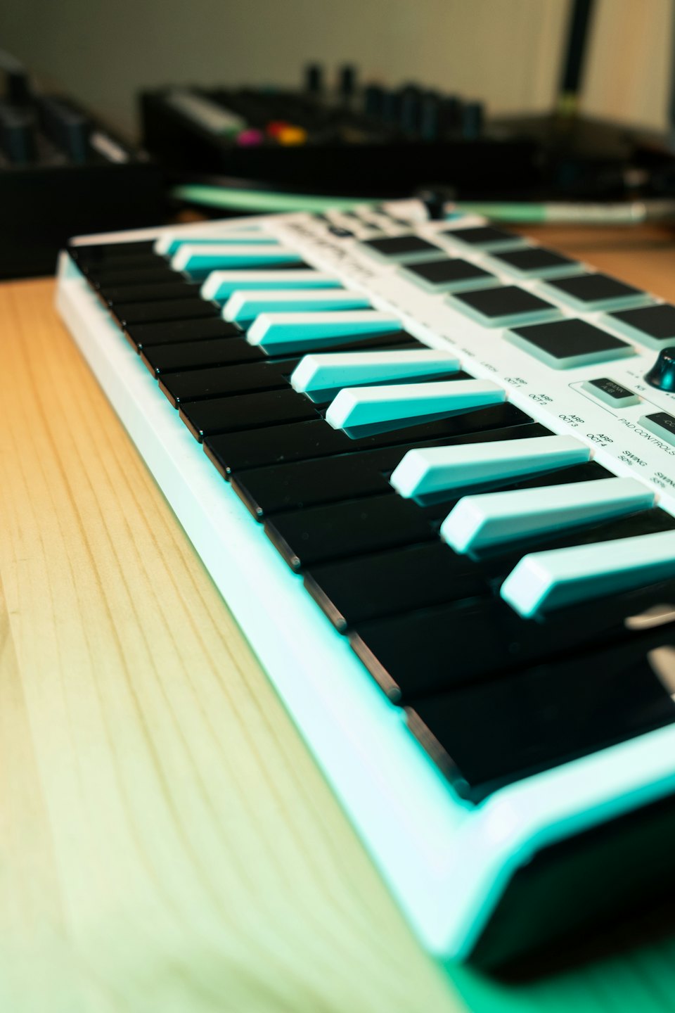 A black and white MIDI keyboard sits on a wooden desk.