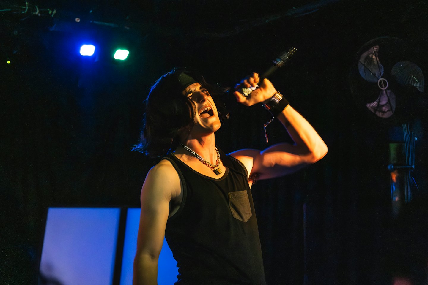 Singer with a lock necklace performing on stage.