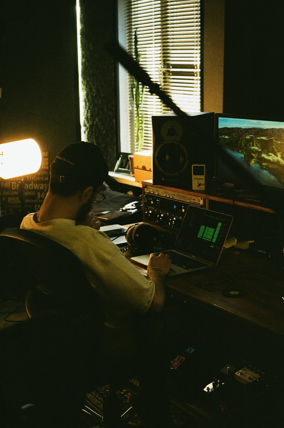 Man works on laptop in home music studio.
