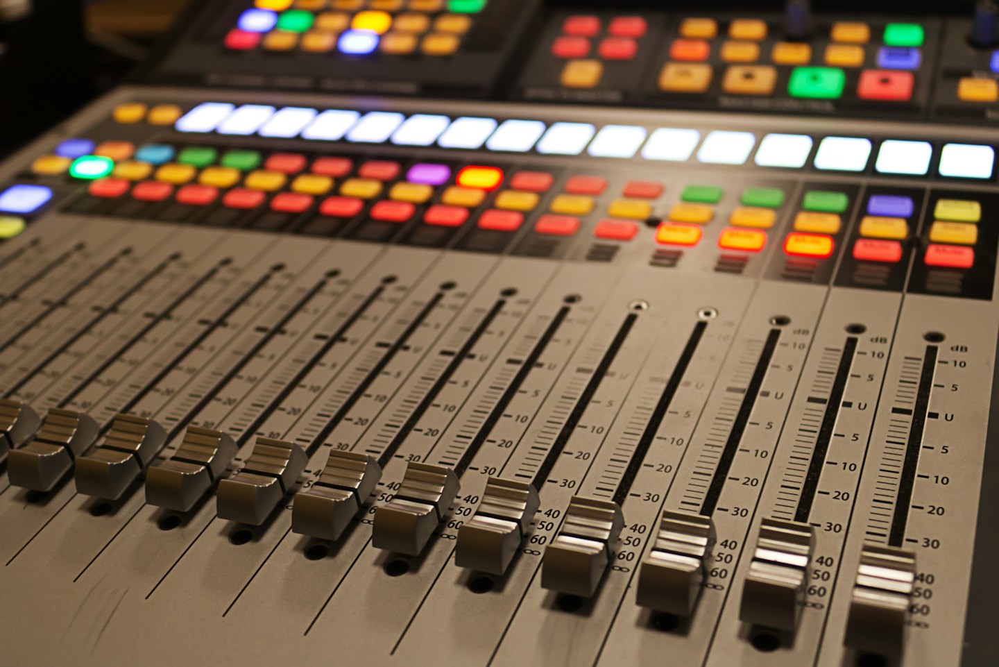 Professional audio mixing console with illuminated buttons and faders.