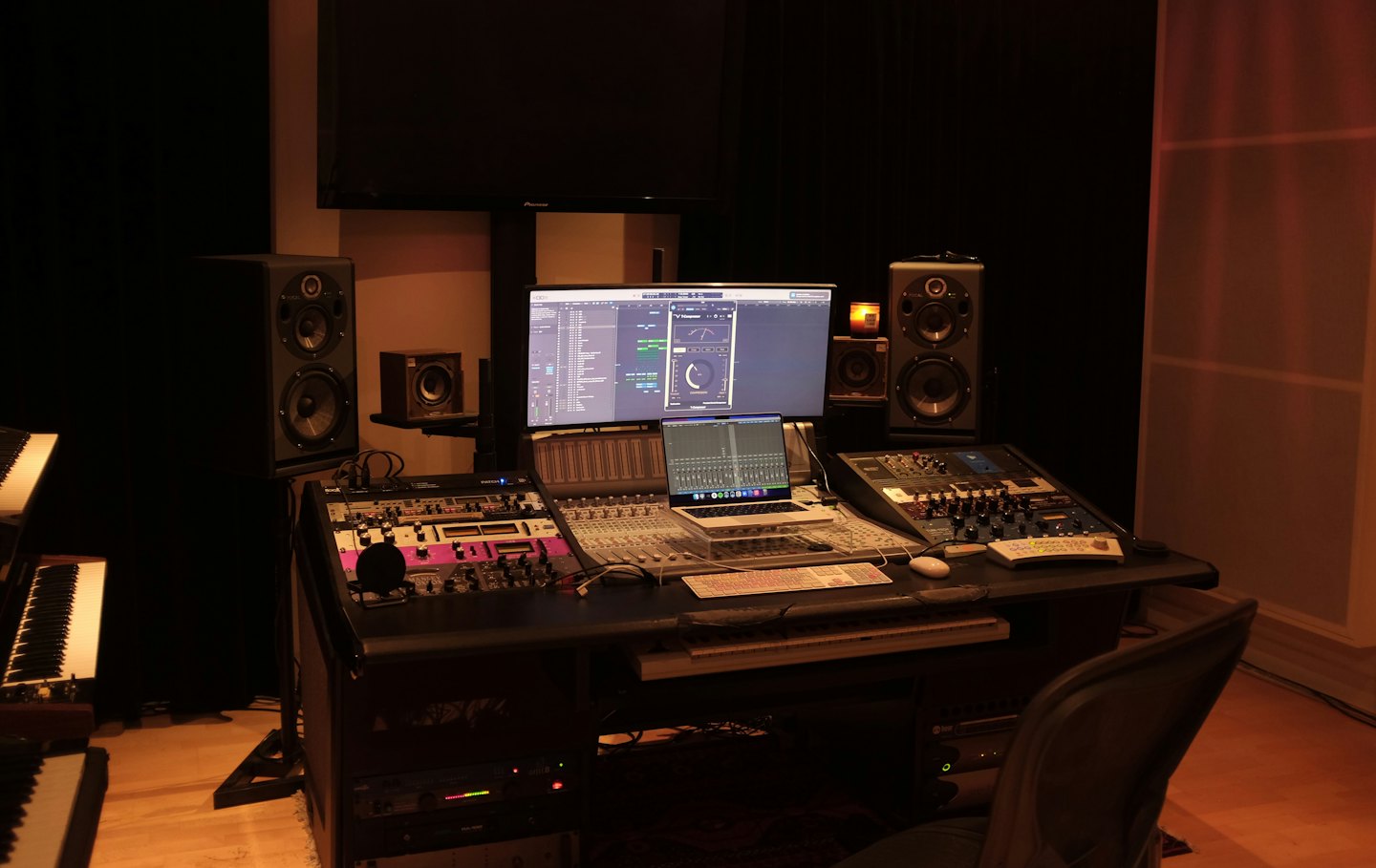 A modern music recording studio desk with audio equipment and computers.